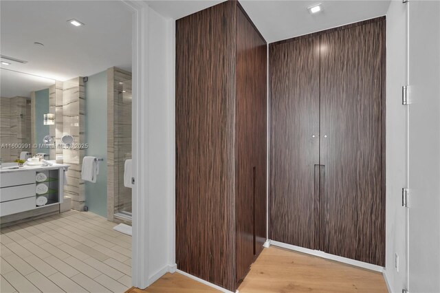 bathroom with wood-type flooring, vanity, and a shower with shower door