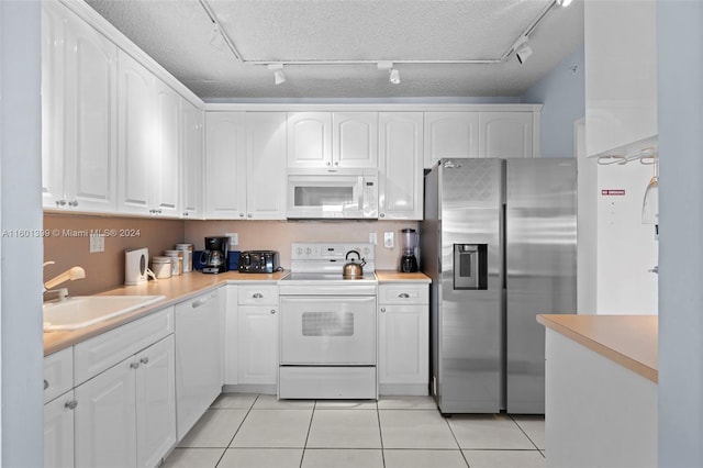 kitchen with rail lighting, a sink, white cabinets, white appliances, and light tile patterned flooring