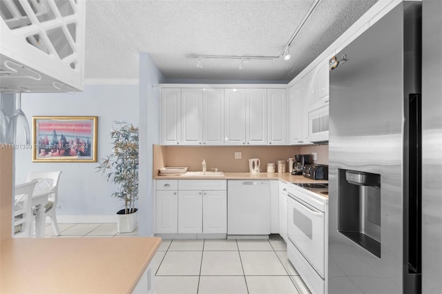 kitchen featuring light tile patterned floors, light countertops, white cabinets, a sink, and white appliances