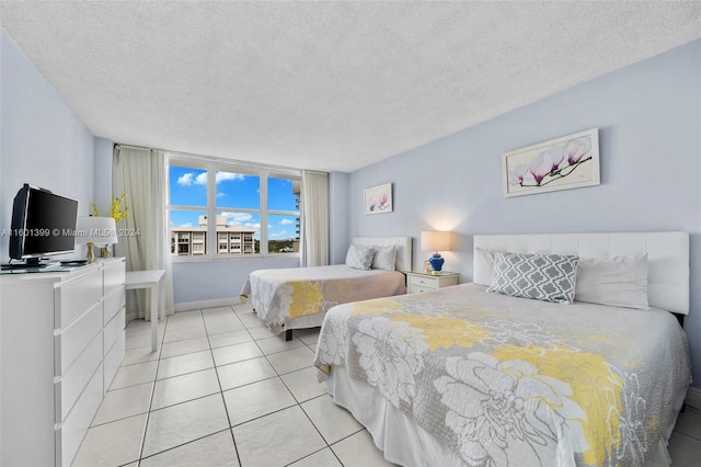 bedroom featuring light tile patterned floors, baseboards, and a textured ceiling