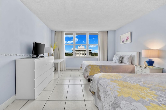 bedroom featuring light tile patterned flooring, baseboards, and a textured ceiling