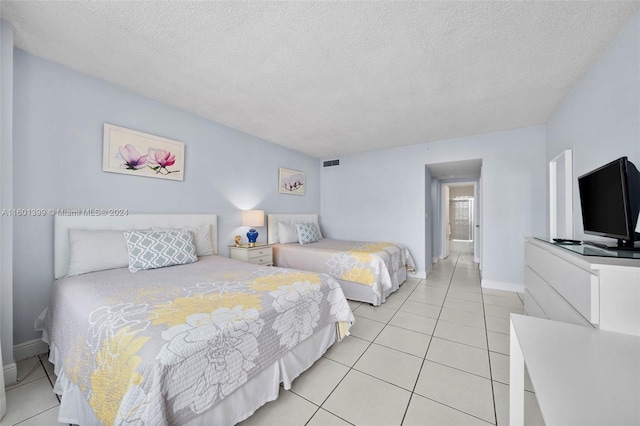 bedroom with baseboards, a textured ceiling, visible vents, and light tile patterned floors