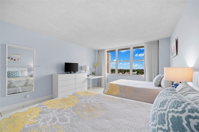 tiled bedroom featuring baseboards and a textured ceiling