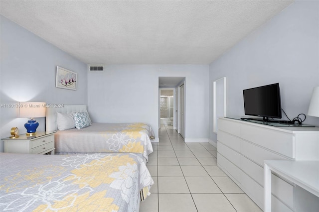 tiled bedroom with a textured ceiling and connected bathroom