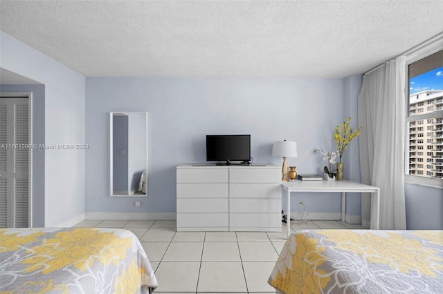 bedroom with a textured ceiling, a closet, and light tile patterned floors