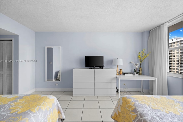 bedroom featuring baseboards, a textured ceiling, and light tile patterned floors
