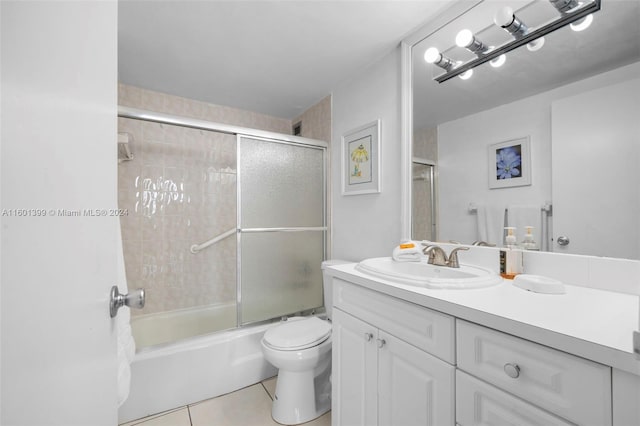 full bathroom with shower / bath combination with glass door, tile patterned flooring, vanity, and toilet