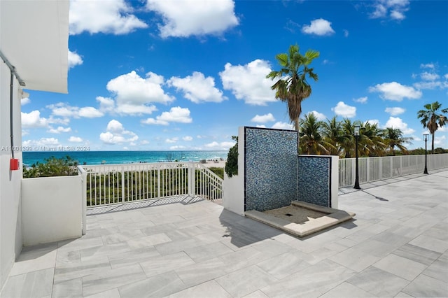 view of patio / terrace with a water view, a balcony, and a view of the beach