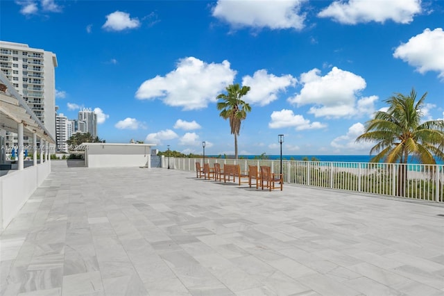 view of patio with fence and a water view