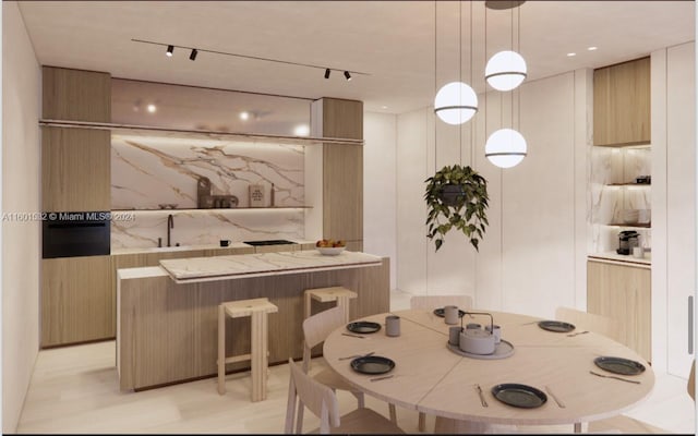 dining area featuring light hardwood / wood-style floors, sink, and rail lighting