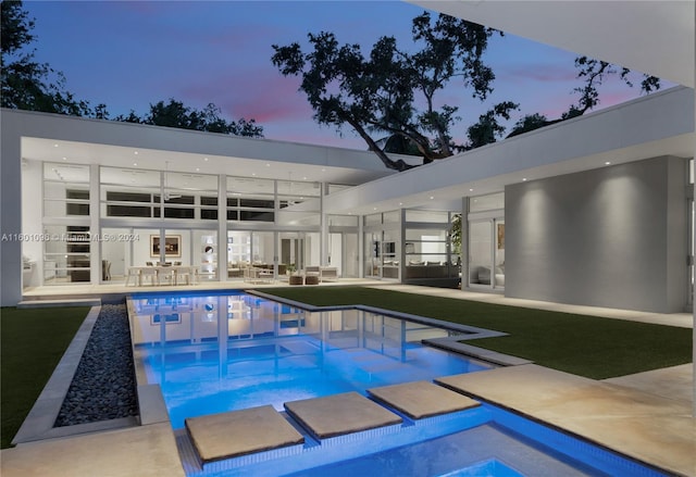 pool at dusk featuring outdoor lounge area, a jacuzzi, and a patio