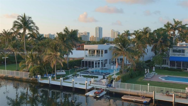 back house at dusk with a yard and a water view