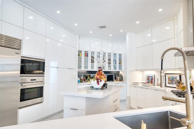 kitchen featuring built in appliances, a center island, and white cabinets