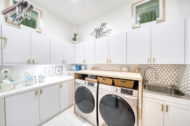 laundry room with light tile patterned flooring, cabinets, sink, and washing machine and clothes dryer