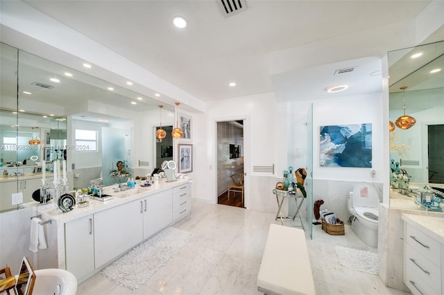 bathroom with vanity, tile walls, and toilet