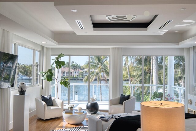 sunroom / solarium featuring a water view, a raised ceiling, and a wealth of natural light