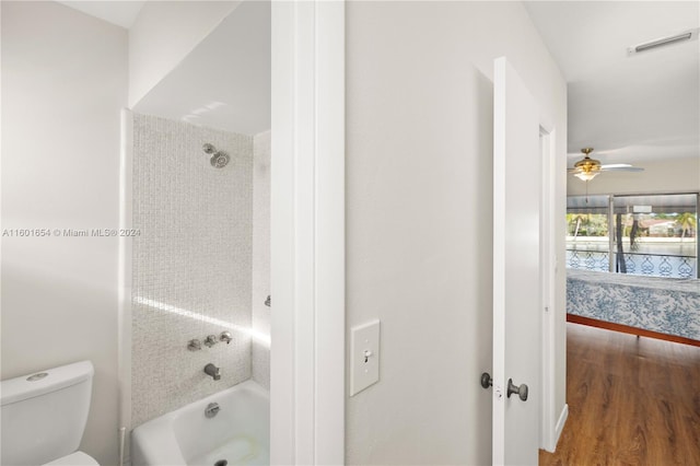 bathroom featuring tiled shower / bath, ceiling fan, toilet, and hardwood / wood-style flooring