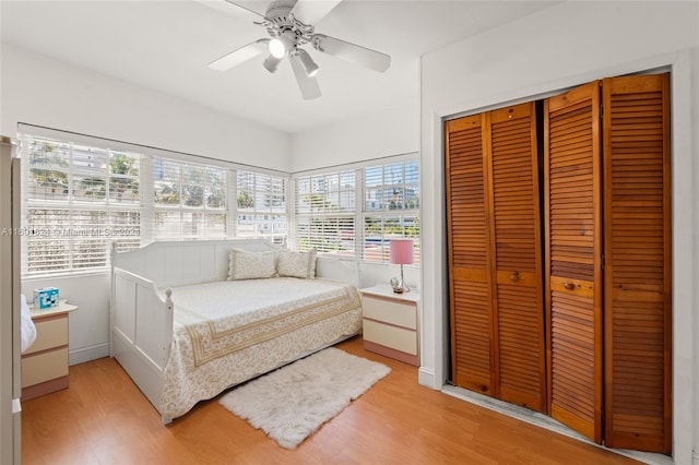 bedroom featuring a closet, light wood-type flooring, multiple windows, and ceiling fan