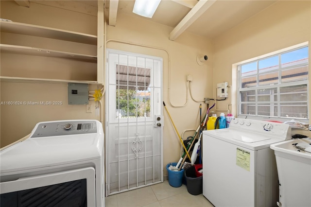 clothes washing area with sink, light tile patterned floors, electric panel, and a healthy amount of sunlight