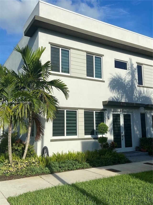 view of front facade with stucco siding and french doors
