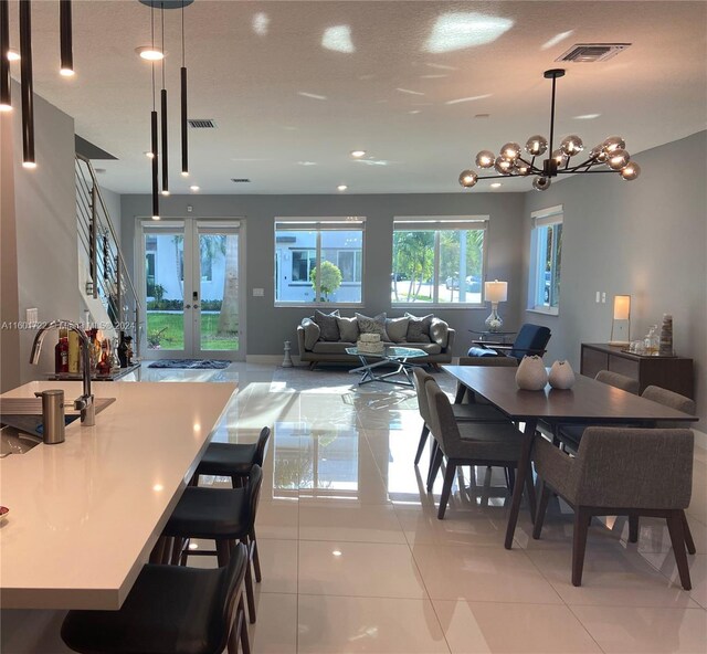 tiled dining area with french doors, an inviting chandelier, and sink