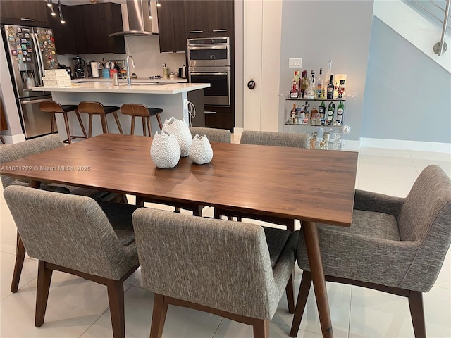 dining area with light tile patterned flooring, baseboards, and bar area
