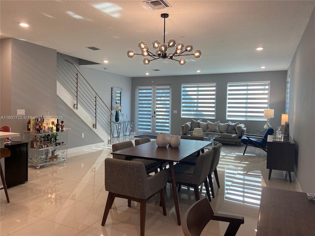 dining area with an inviting chandelier, a dry bar, stairway, and visible vents