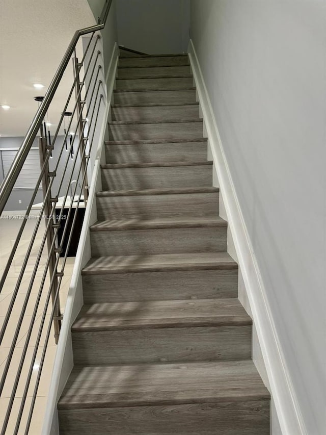 stairway featuring baseboards, wood finished floors, and recessed lighting