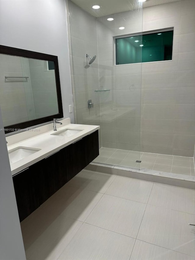 full bathroom featuring double vanity, a sink, tile patterned flooring, and walk in shower