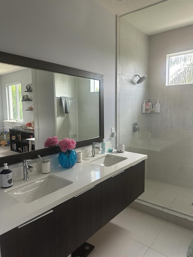 bathroom featuring double vanity, a sink, a tile shower, and tile patterned floors