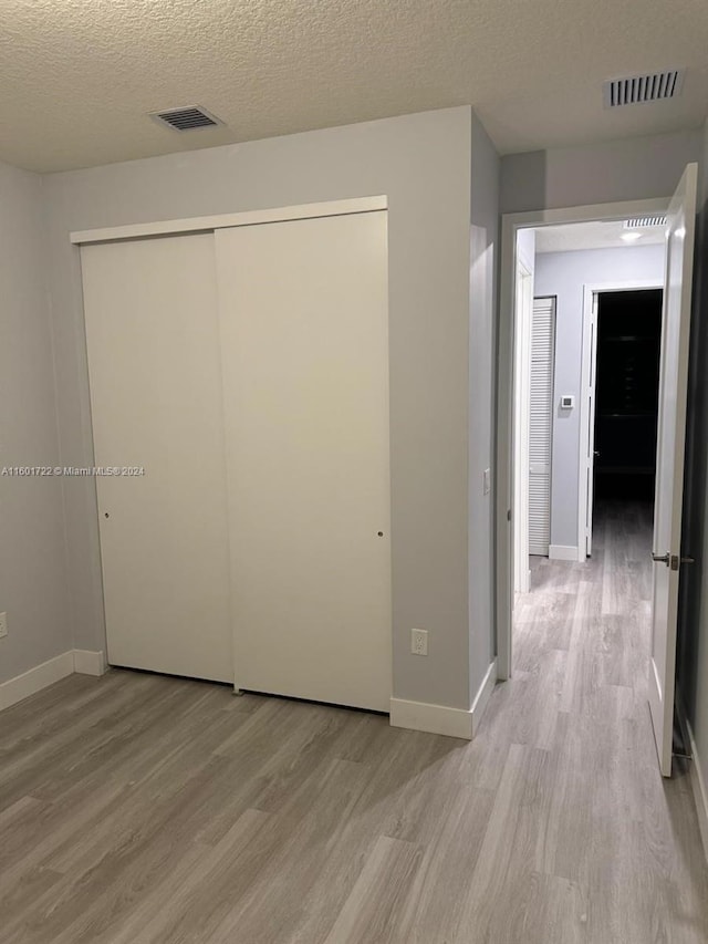 hall with a textured ceiling and light hardwood / wood-style floors