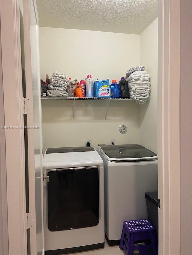 washroom with washer and dryer, laundry area, and a textured ceiling