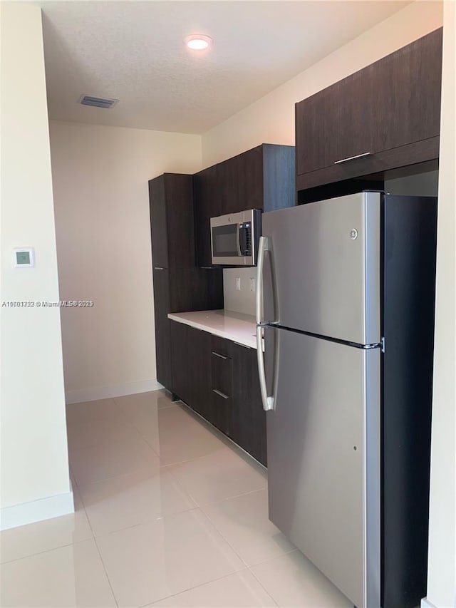 kitchen featuring light countertops, visible vents, modern cabinets, stainless steel appliances, and dark brown cabinetry