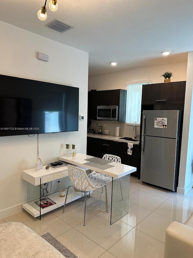 kitchen with light countertops, light tile patterned floors, stainless steel appliances, a sink, and visible vents