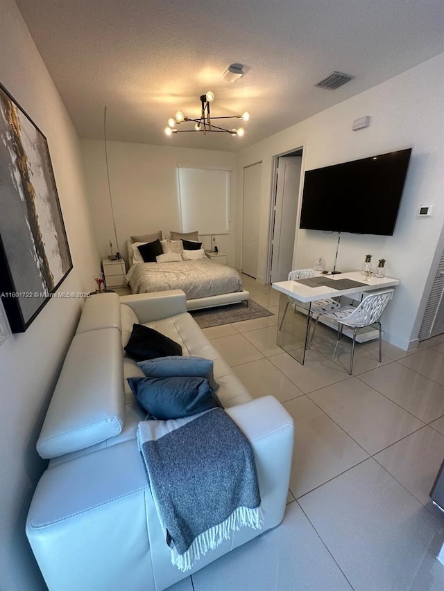 living area featuring a textured ceiling, visible vents, an inviting chandelier, and light tile patterned floors