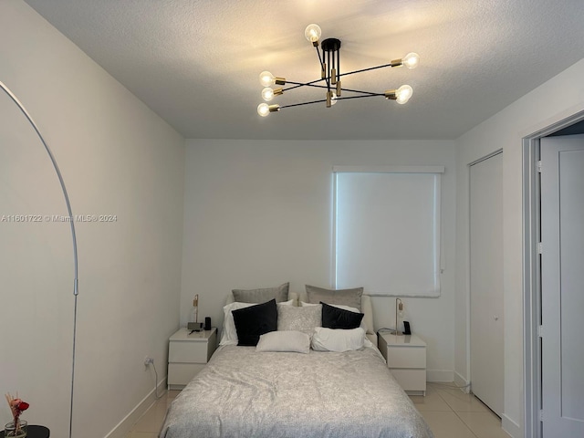 tiled bedroom featuring a textured ceiling and a notable chandelier