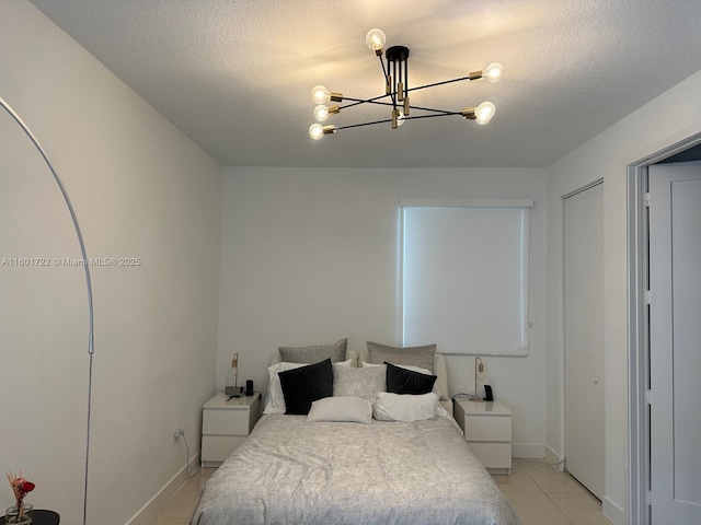bedroom with light tile patterned floors, a textured ceiling, baseboards, and a notable chandelier
