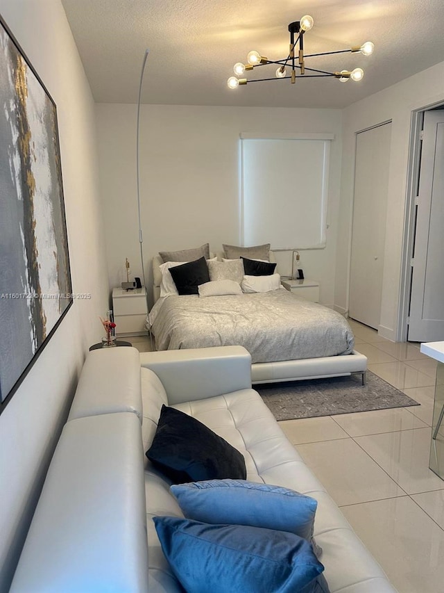 bedroom featuring a textured ceiling, an inviting chandelier, and light tile patterned floors