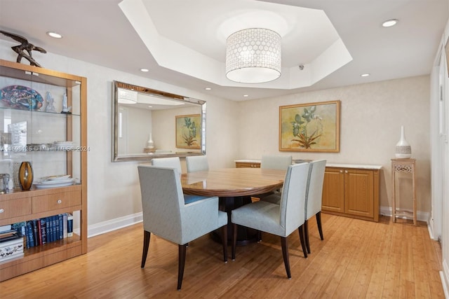 dining area featuring light hardwood / wood-style floors and a raised ceiling