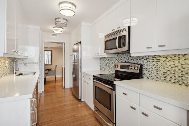 kitchen with sink, white cabinetry, tasteful backsplash, light hardwood / wood-style flooring, and stainless steel appliances