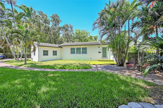rear view of property with stucco siding, a tiled roof, and a yard