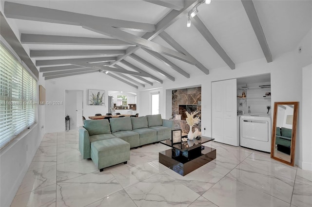 living area featuring washer and dryer, vaulted ceiling with beams, a wealth of natural light, and marble finish floor