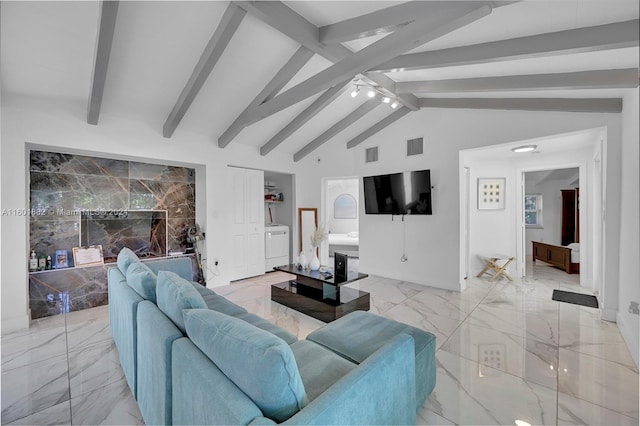living area with visible vents, lofted ceiling with beams, washing machine and dryer, and marble finish floor