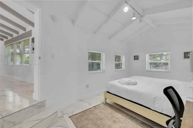 bedroom with rail lighting, lofted ceiling with beams, marble finish floor, and multiple windows