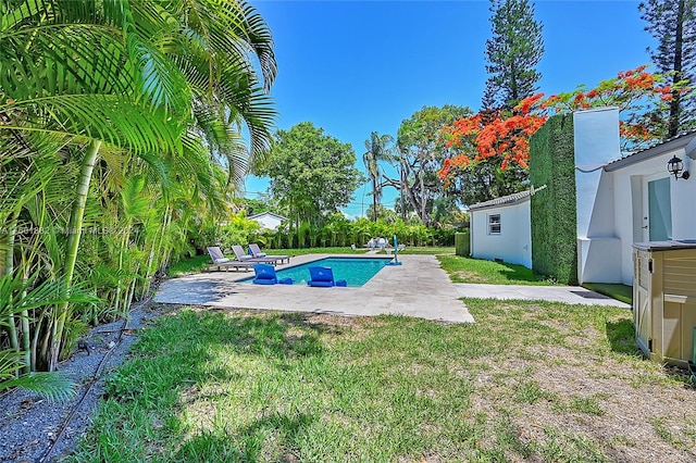 view of pool with a lawn, a storage shed, and a patio area