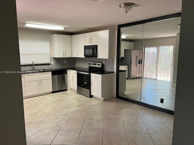 kitchen featuring sink, light tile patterned floors, a textured ceiling, white cabinetry, and stainless steel appliances