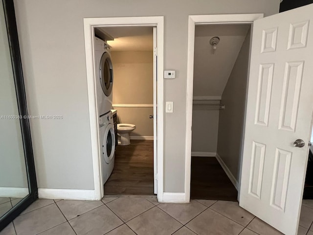 laundry area featuring light tile patterned flooring and stacked washing maching and dryer