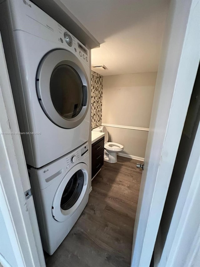 washroom featuring dark hardwood / wood-style floors and stacked washer / dryer