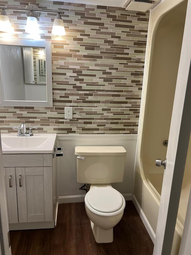 bathroom with decorative backsplash, vanity, hardwood / wood-style flooring, and toilet