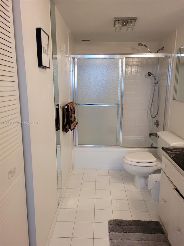 full bathroom with shower / bath combination with glass door, tile patterned floors, vanity, and toilet